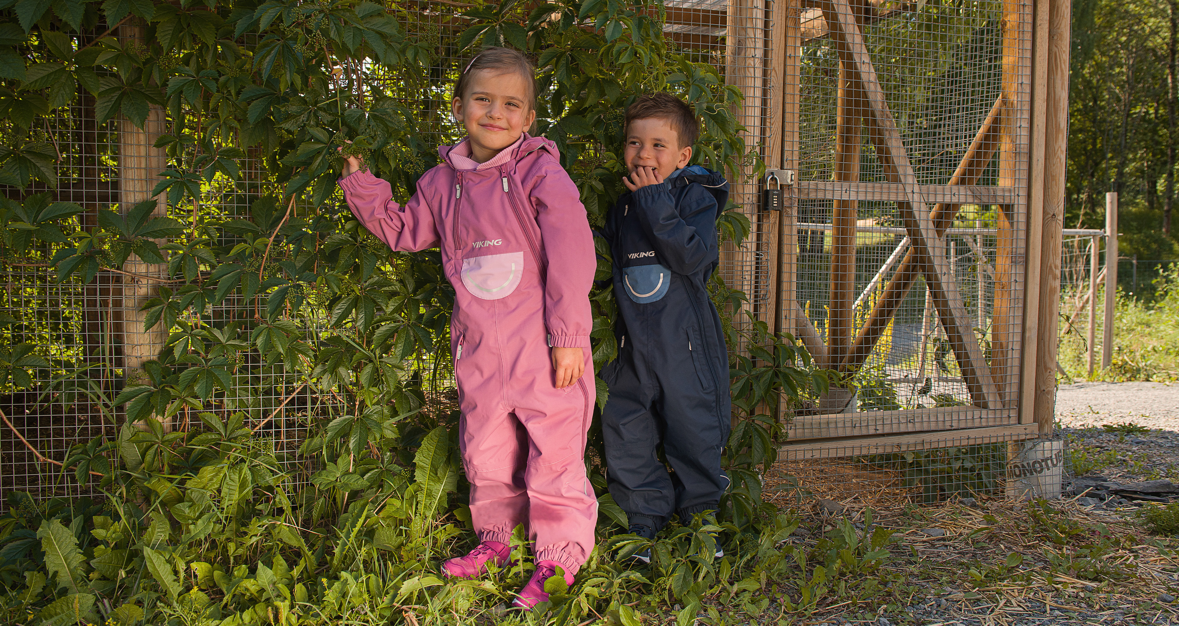 wo smiling children wearing durable and weather-protective playsuits from Viking, ready for outdoor play