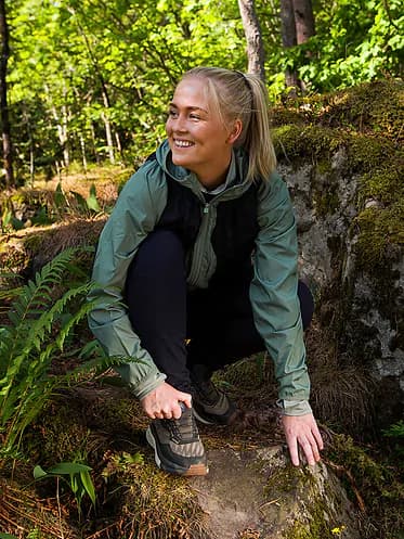 Female hiker adjusting the BOA dial on her hiking shoe in the forest